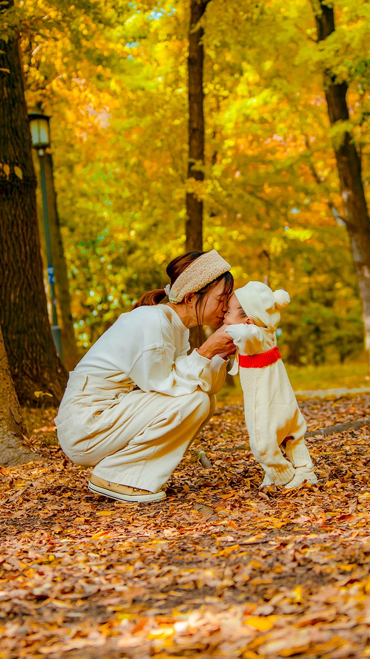 紅葉と落ち葉の中、子供の顔に顔をくっつける母