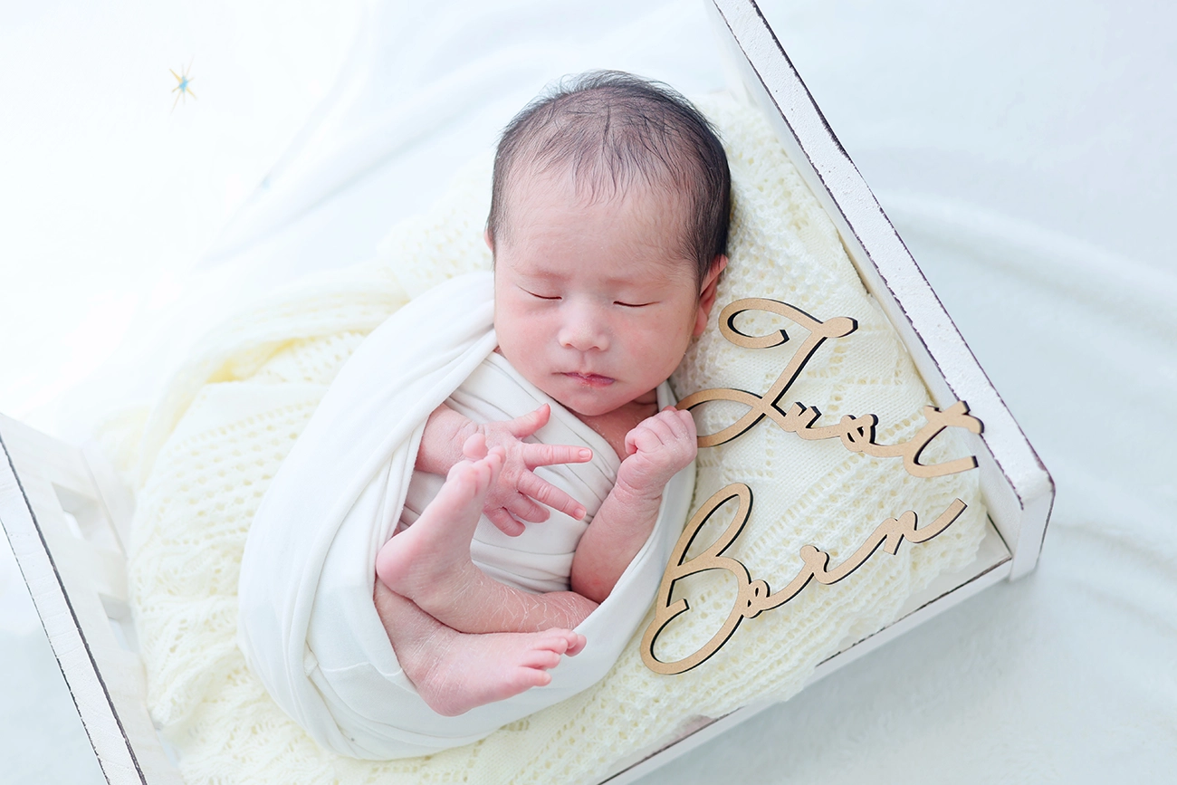 白い布に包まれる赤ちゃんのニューボーンフォト