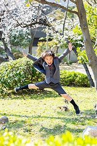 桜の木の下で元気にジャンプする男の子