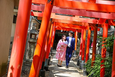 お宮参りで赤い鳥居の中を歩く夫婦と赤ちゃん