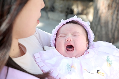 お宮参りで母の腕の中で泣く赤ちゃん