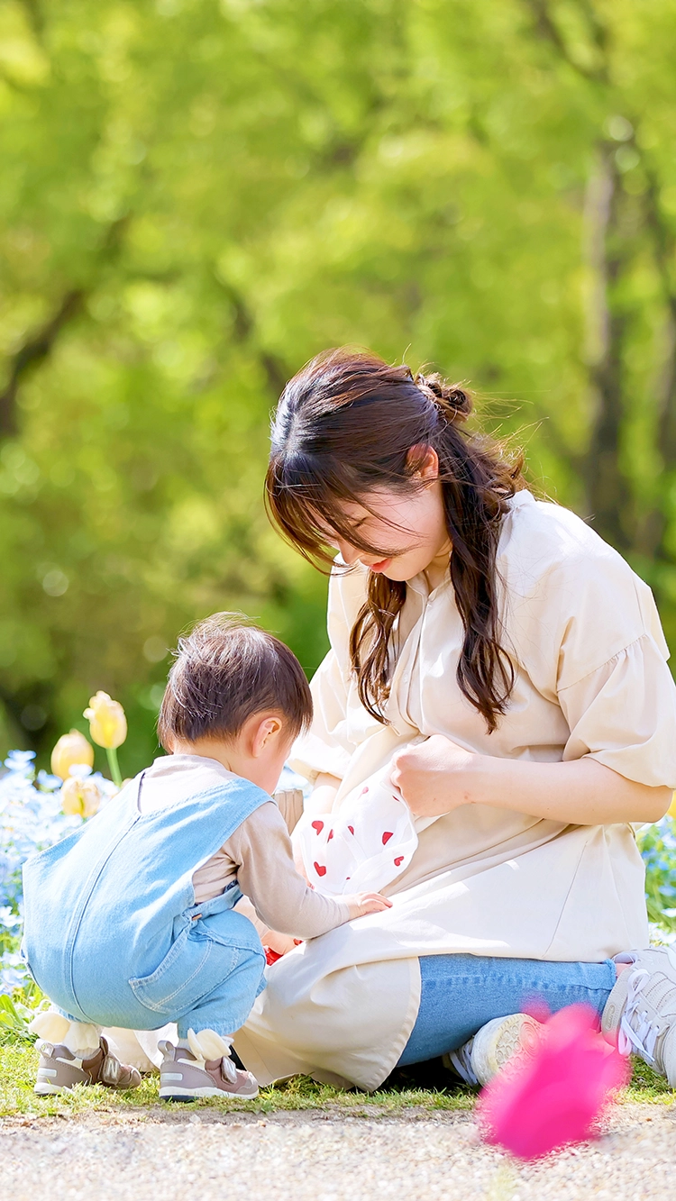 メインビジュアル：花畑で向き合い笑顔の親子